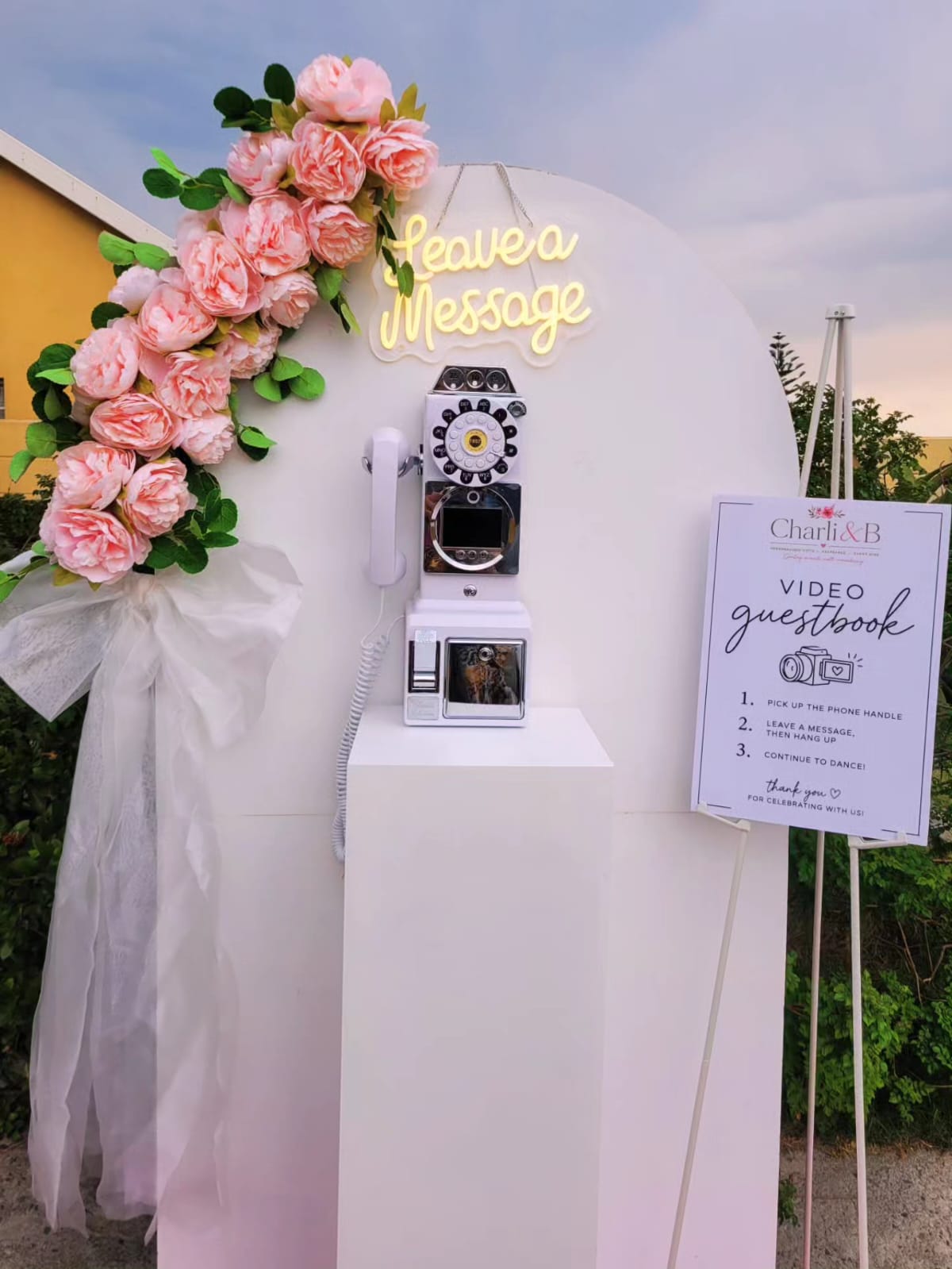 Video guestbook stand with pink roses and white tulle bow